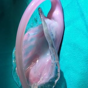 A hand blown glass pink and clear dish with a handle.